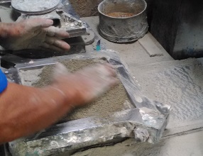 Production of encaustic tiles. A layer of dry cement is applied to absorb some of the moisture.